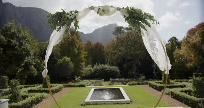 Wedding arch with decorations in sunny summer garden with swimming pool, in slow motion