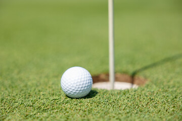 golf ball close to going into the hole cup with the flag still