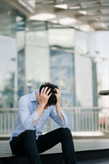 Frustrated young Asian businessman working on a laptop computer sitting at his working place in outside office