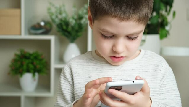The child uses the phone, holds the smartphone in his hand and looks at the screen. Screen Time, Parental Controls