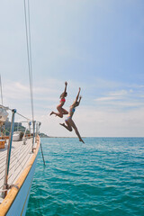 Summer, sailing and friends jumping off a yacht together into the ocean for freedom, fun or...