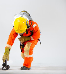 Firefighter wearing a vibrant yellow helmet carefully pick up the fire hose from the floor.