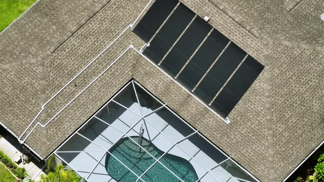 Plastic solar heating panels installed on rooftop of a private house for warming of swimming pool water in cold season. Renewable sun energy used to heat pool