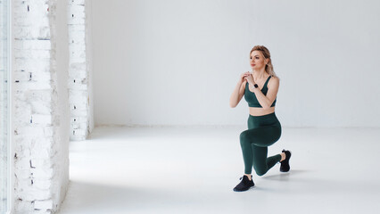 Focused fitness girl squatting with kneeling in the studio on a white background