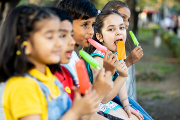 Group of kids having ice cream during summer camp .Kids having ice colorful ice candy enjoying summers