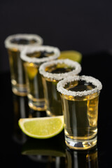Tequila in a glass served with limes and salt.