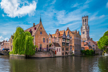 Historic buildings along a canal and the Belfort tower in Bruges, Belgium