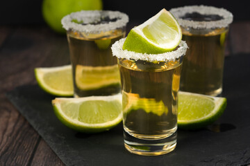 Tequila in a glass served with limes and salt.