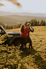 Young couple relaxing by a terrain vehicle hood at countryside