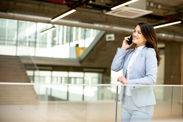 Young business woman using mobile phone in the office hallway