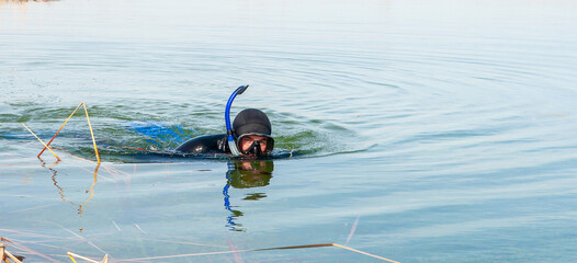 The diver swims in a wetsuit, flippers and a mask with a tube. The rescuer divers carries out work under water.