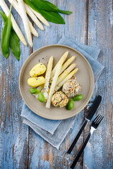 Traditional Bavarian white asparagus with wild garlic- and almond butter dumpling served as top view on a Nordic Design plate with text space