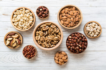 mixed nuts in wooden bowl. Mix of various nuts on colored background. pistachios, cashews, walnuts, hazelnuts, peanuts and brazil nuts