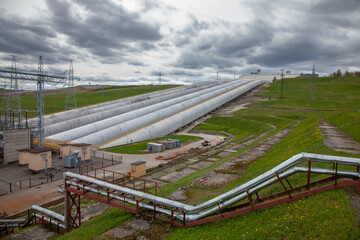 Fototapeta na wymiar hydro power plant pipes on grey sky background