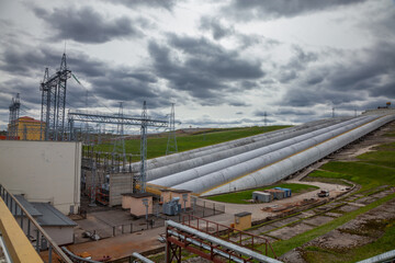 hydro power plant pipes and electric substation on grey sky background