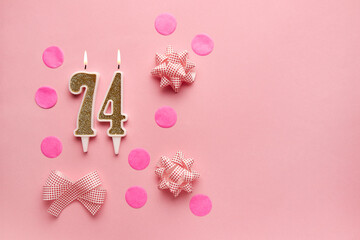 Number 74 on pastel pink background with festive decor. Happy birthday candles. The concept of celebrating a birthday, anniversary, important date, holiday. Copy space. banner