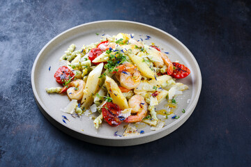 White asparagus glazed with fried king prawns and pistachio pasta served as close-up on a design plate with text space