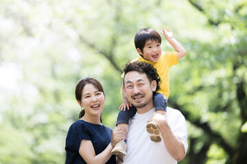 新緑の中子どもと肩車をする幸せそうな家族