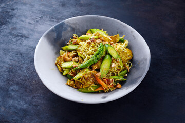 Traditional Thai Pad Mama with Instand noodles, chicken and green asparagus served as a close-up on a design plate with text space