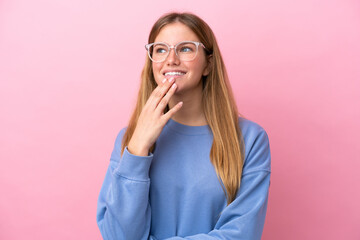 Young blonde woman isolated on pink background With glasses and thinking while looking up