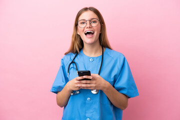 Young surgeon doctor woman isolated on pink background surprised and sending a message