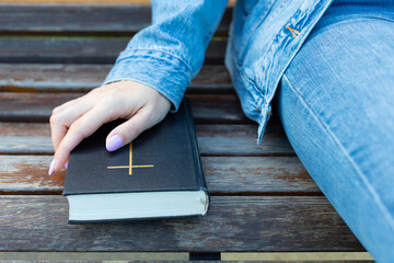 woman holding her hand on the bible lying on the bench