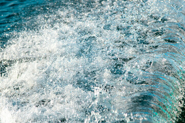 Waves on the sandy beach. Water background, blue sea water. Beautiful texture of sun glare on the...