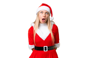 Young blonde woman with christmas hat over isolated chroma key background looking up and with surprised expression