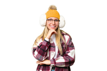 Young pretty blonde woman wearing winter muffs over isolated chroma key background with glasses and...