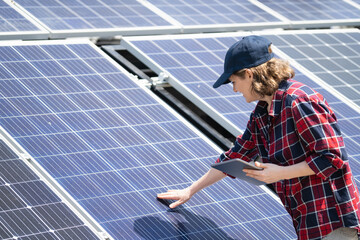 Woman with digital tablet touching solar panel