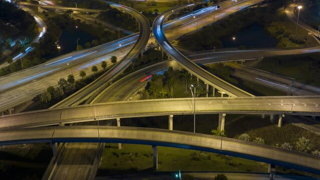 Timelapse of american freeway intersection at night with fast driving cars and trucks in Miami, Florida. View from above of USA transportation infrastructure