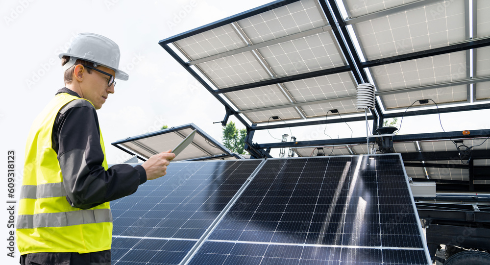 Poster Engineer with tablet computer on a background of mobile solar energy power station