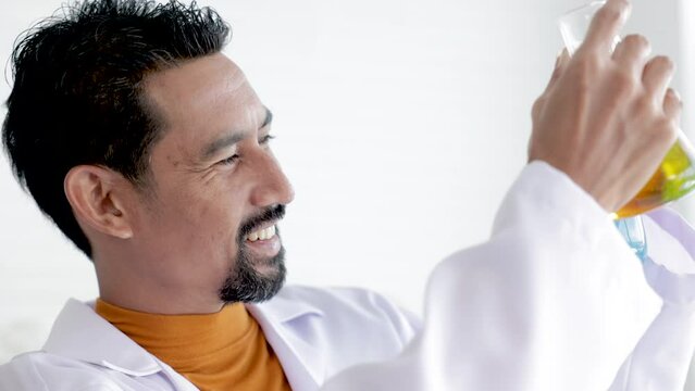 Asian male scientist analyzing Liquid Biochemicals in Laboratory Flask. Advanced Scientific Biotechnology Laboratory,  processing of laboratory sample in a flask, titration with reagent from a burette