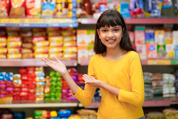 Indian girl giving expression with hand at grocery shop.