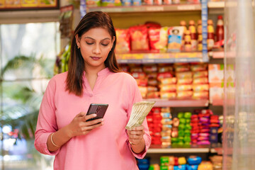 Indian woman using smartphone at grocery shop.