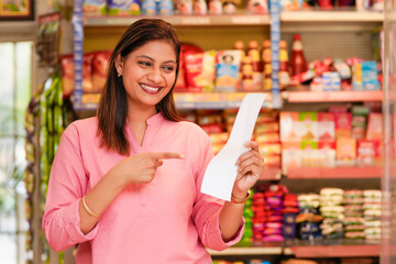 Indian woman checking list at grocery shop.