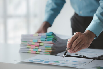 A business finance man is reviewing a company's financial documents prepared by the Finance...