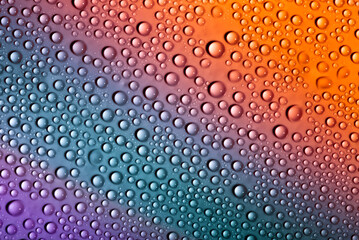 Water drops on glass as a background. Condensation on a cold drink. Multicolored background with drops texture.