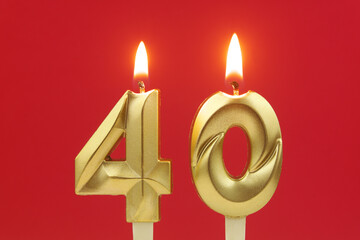 Golden birthday candles burning and melting on red background, number 40
