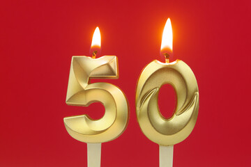 Golden birthday candles burning and melting on red background, number 50