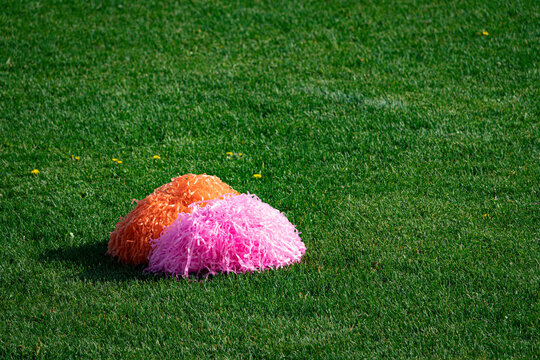 cheerleading pom-poms in the grass on a football field