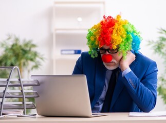 Old businessman clown working in the office