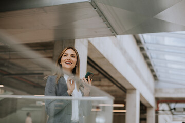 Young business woman using mobile phone in the office hallway