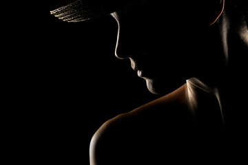Sensual portrait silhouette of beautiful woman with a hat in backlight on a black studio background