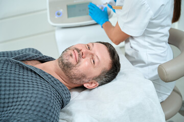 Smiling male with unshaven lies on a cosmetology couch