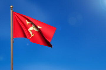 Isle of Man. Flag blown by the wind with blue sky in the background.