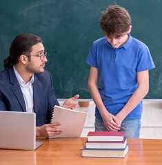 Young male teacher and schoolboy in the classroom