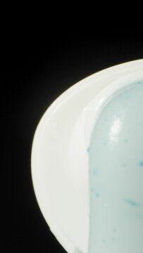 I squeeze out white toothpaste on a black background. Dolly slider extreme close-up. Vertical video Social Media