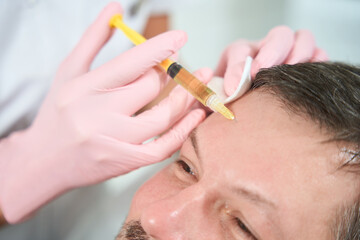 Unshaven male gets subcutaneous injections of the frontal zone