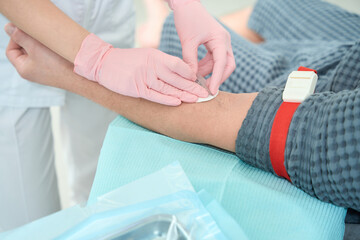 Doctor in protective gloves takes blood from a patient